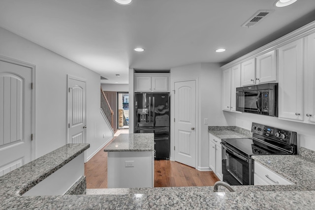 kitchen with a kitchen island, black appliances, white cabinetry, and light stone counters