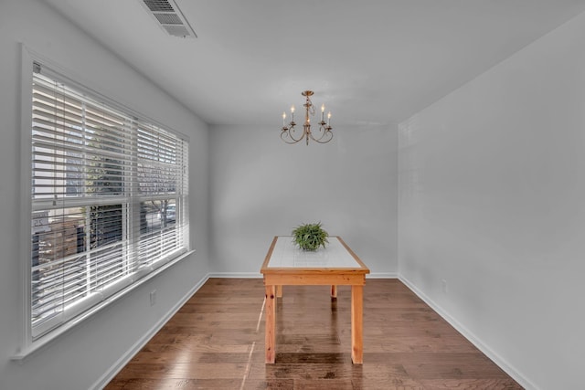 unfurnished dining area with an inviting chandelier and wood-type flooring