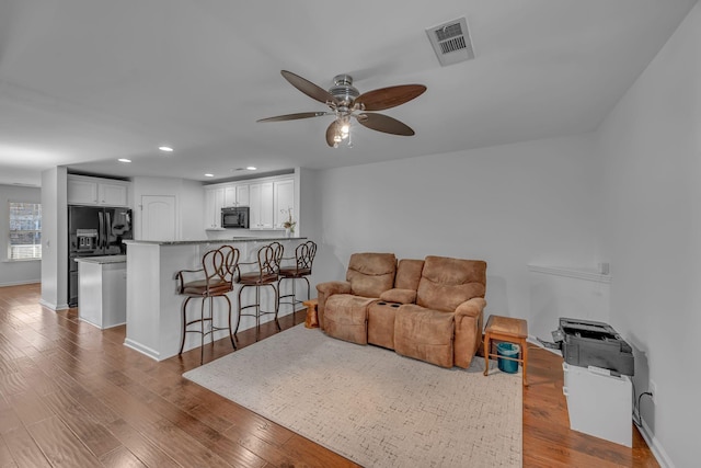 living room featuring wood-type flooring and ceiling fan