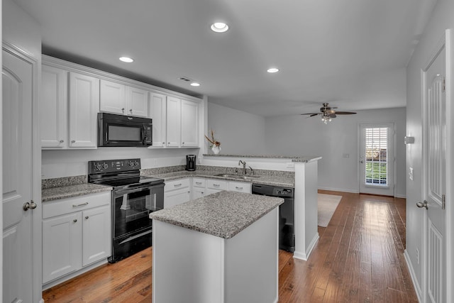 kitchen with white cabinetry, black appliances, and a kitchen island