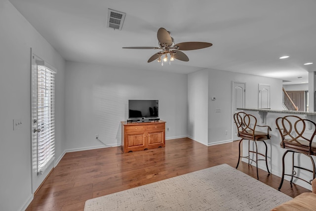 living room featuring dark wood-type flooring and ceiling fan