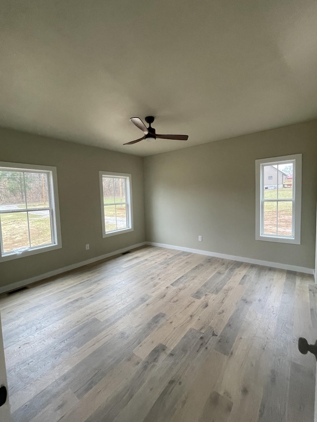 empty room with ceiling fan and light hardwood / wood-style flooring