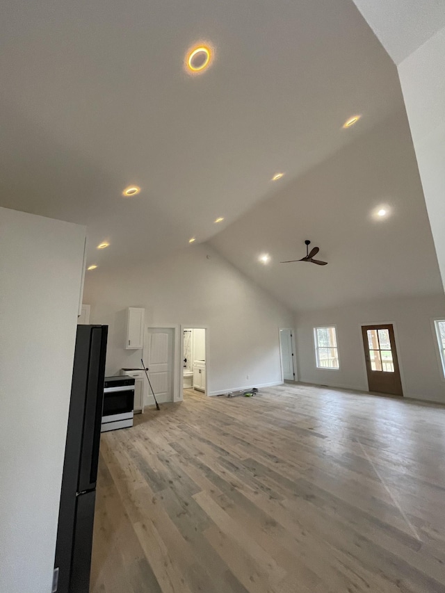 unfurnished living room featuring light wood-type flooring, high vaulted ceiling, and ceiling fan