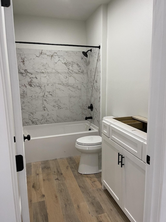 full bathroom featuring vanity, hardwood / wood-style flooring, tiled shower / bath, and toilet