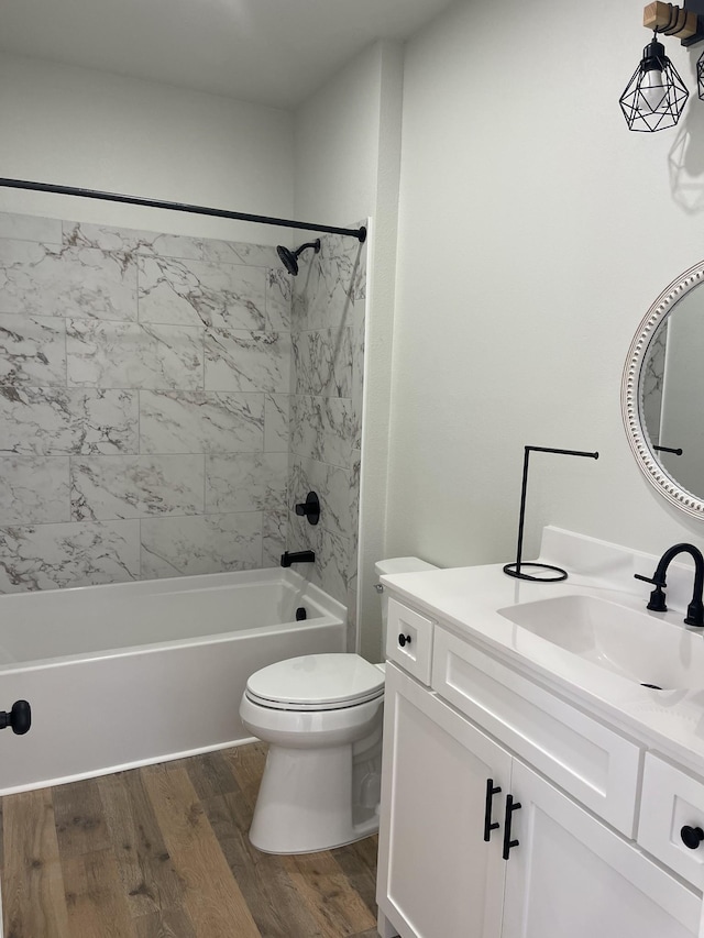 full bathroom featuring hardwood / wood-style flooring, toilet, tiled shower / bath, and vanity