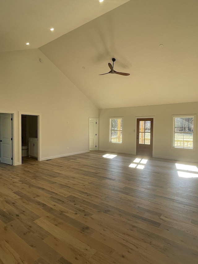 unfurnished living room featuring high vaulted ceiling, dark hardwood / wood-style floors, and a healthy amount of sunlight