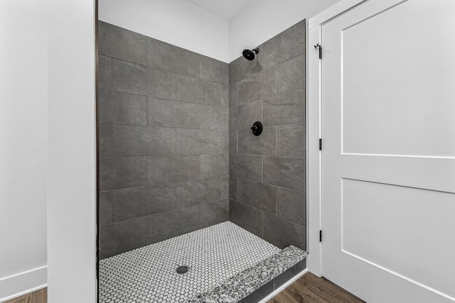 bathroom with tiled shower and hardwood / wood-style floors