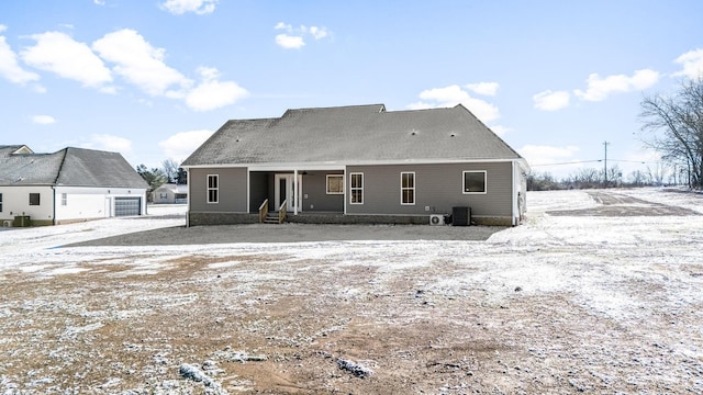 snow covered rear of property featuring central AC