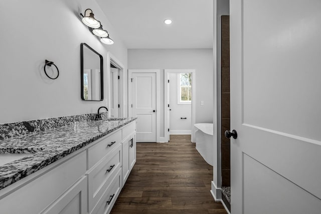 bathroom with hardwood / wood-style floors, a tub to relax in, and vanity