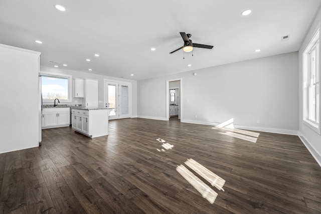 unfurnished living room featuring ceiling fan, sink, and dark hardwood / wood-style flooring