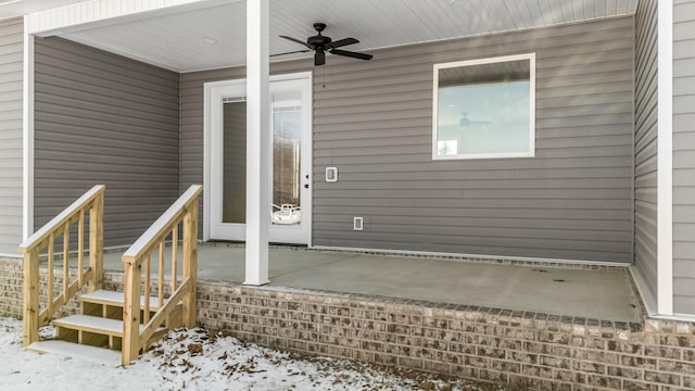 snow covered property entrance featuring ceiling fan and a patio