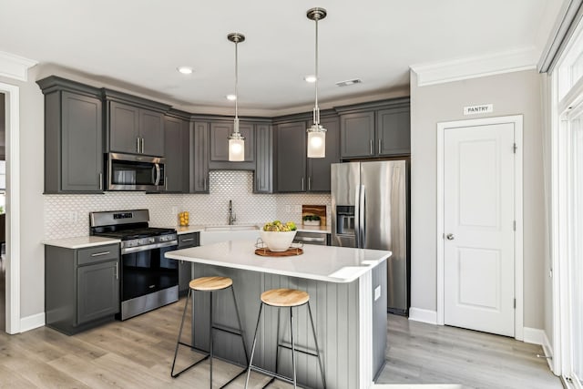 kitchen with sink, appliances with stainless steel finishes, pendant lighting, and gray cabinets