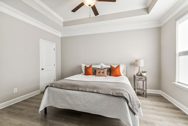 bedroom featuring ceiling fan, wood-type flooring, ornamental molding, and a raised ceiling