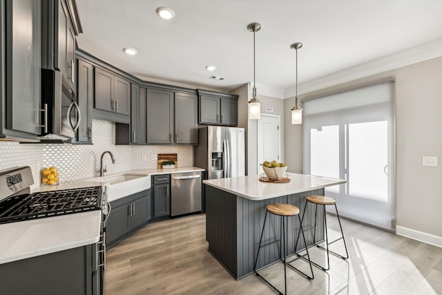 kitchen with hanging light fixtures, appliances with stainless steel finishes, light wood-type flooring, tasteful backsplash, and a kitchen island