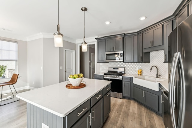 kitchen featuring sink, decorative light fixtures, backsplash, a center island, and stainless steel appliances