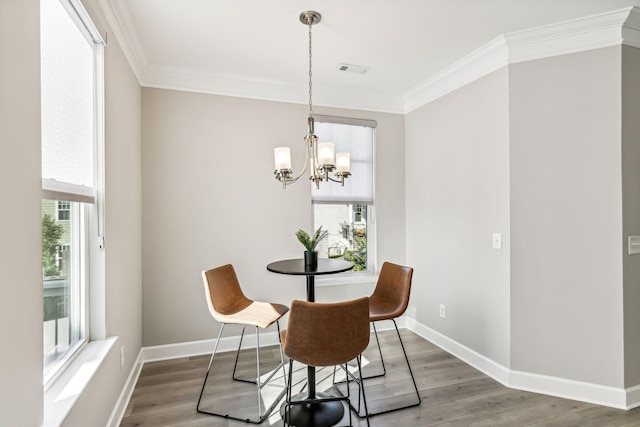 dining area with ornamental molding, a chandelier, a healthy amount of sunlight, and hardwood / wood-style floors