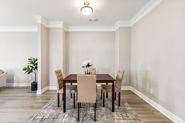 dining area featuring hardwood / wood-style flooring and crown molding