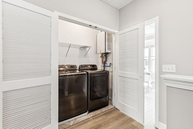 clothes washing area with light hardwood / wood-style floors and washer and clothes dryer