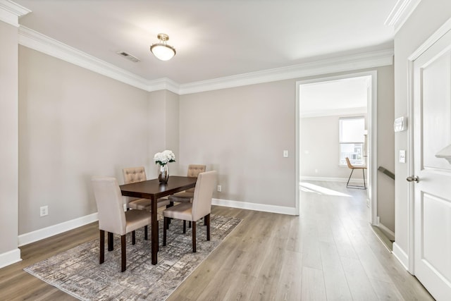 dining area featuring crown molding and light hardwood / wood-style floors