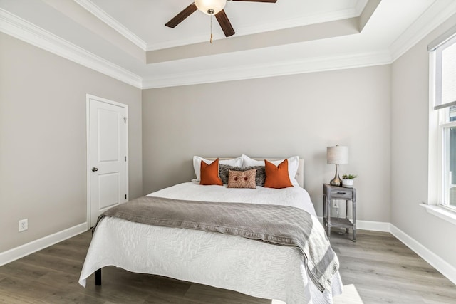 bedroom featuring ceiling fan, hardwood / wood-style floors, a tray ceiling, and crown molding