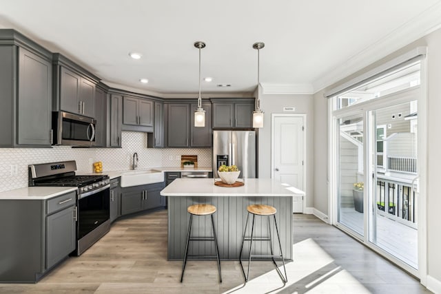 kitchen featuring decorative backsplash, gray cabinetry, sink, pendant lighting, and stainless steel appliances