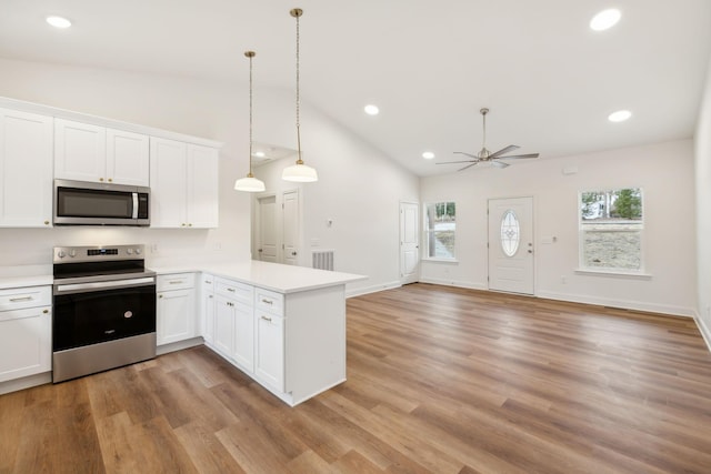 kitchen with kitchen peninsula, white cabinetry, decorative light fixtures, and stainless steel appliances