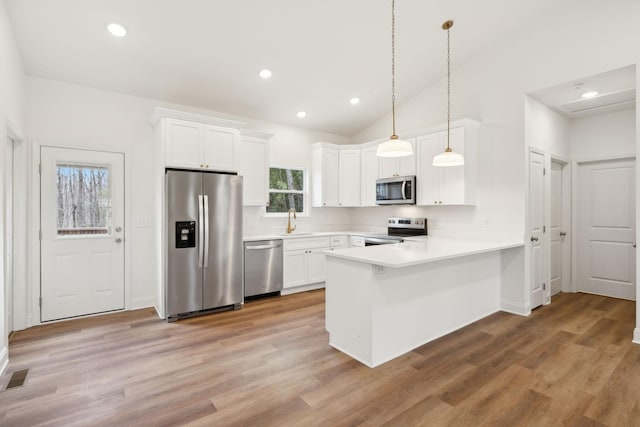 kitchen with stainless steel appliances, white cabinetry, kitchen peninsula, and pendant lighting