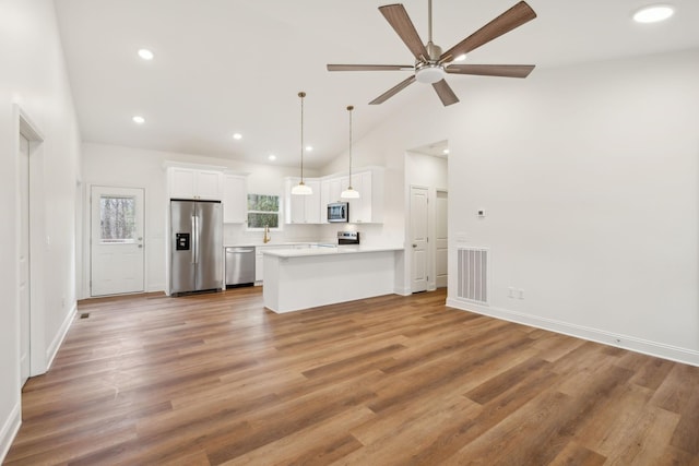 kitchen with pendant lighting, white cabinets, lofted ceiling, stainless steel appliances, and tasteful backsplash