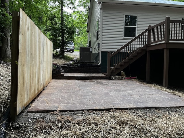 view of property exterior featuring stairway, a patio, a wooden deck, and central air condition unit