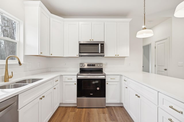 kitchen featuring sink, stainless steel appliances, hanging light fixtures, and white cabinets