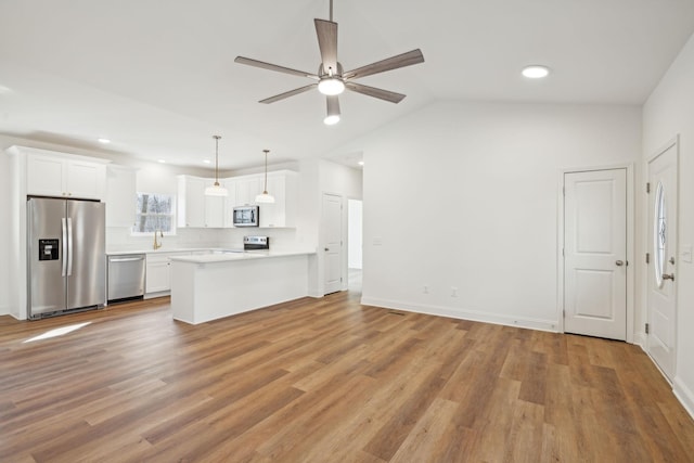 kitchen with lofted ceiling, white cabinetry, stainless steel appliances, hanging light fixtures, and kitchen peninsula