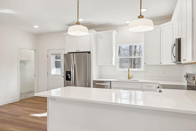 kitchen featuring sink, hanging light fixtures, white cabinets, and stainless steel appliances