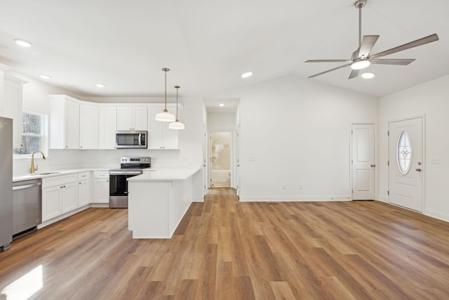 kitchen featuring appliances with stainless steel finishes, sink, decorative light fixtures, light wood-type flooring, and white cabinetry