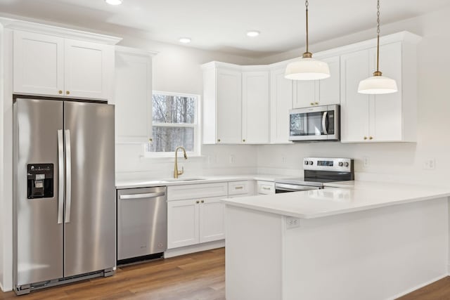 kitchen featuring pendant lighting, white cabinets, stainless steel appliances, sink, and kitchen peninsula