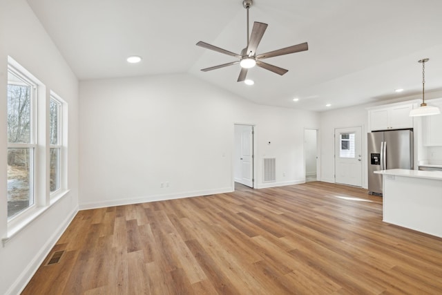 unfurnished living room with a wealth of natural light, light hardwood / wood-style flooring, and vaulted ceiling