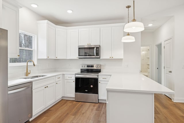 kitchen with sink, white cabinetry, kitchen peninsula, and appliances with stainless steel finishes