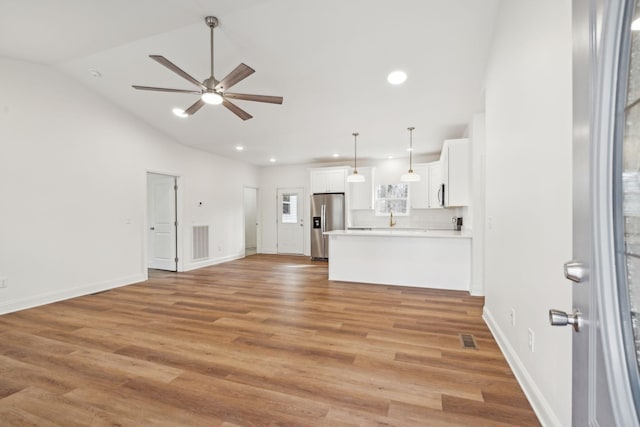 unfurnished living room featuring light wood-type flooring, ceiling fan, and vaulted ceiling