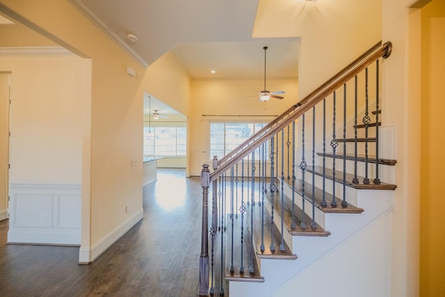 stairs with ornamental molding, hardwood / wood-style floors, and ceiling fan