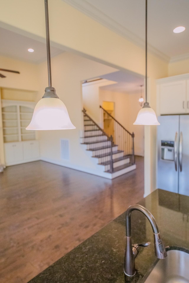 kitchen with dark stone countertops, decorative light fixtures, refrigerator with ice dispenser, and white cabinets