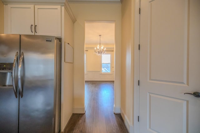 kitchen featuring dark wood-type flooring, white cabinetry, crown molding, stainless steel fridge, and pendant lighting