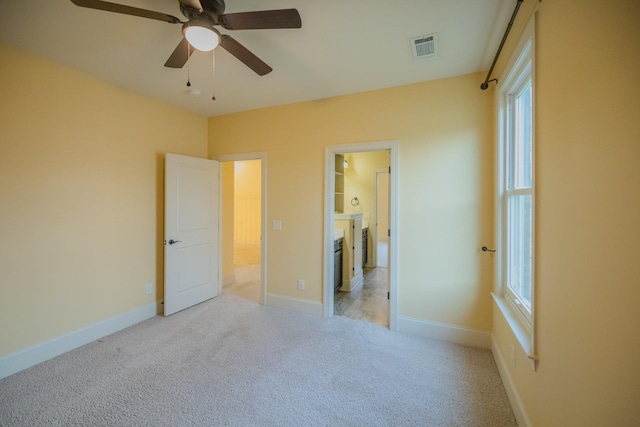 unfurnished bedroom with ceiling fan, light colored carpet, and ensuite bath