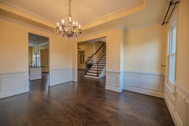 unfurnished room with sink, dark hardwood / wood-style floors, a tray ceiling, ornamental molding, and a chandelier