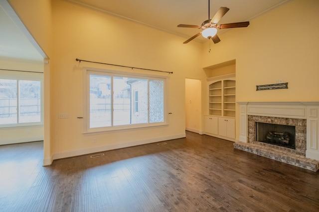 unfurnished living room with crown molding, dark hardwood / wood-style floors, built in features, ceiling fan, and a high ceiling