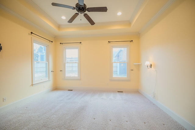 empty room with light carpet, a tray ceiling, ornamental molding, and ceiling fan