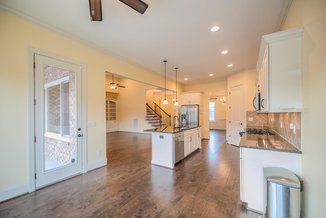 kitchen featuring decorative light fixtures, white cabinetry, a kitchen island with sink, ceiling fan, and stainless steel appliances