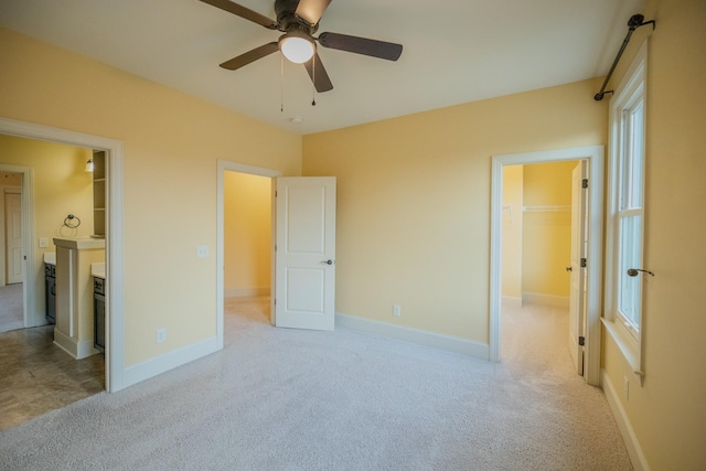 carpeted bedroom with ceiling fan, ensuite bathroom, and a spacious closet