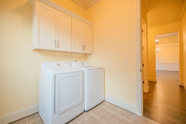 clothes washing area with crown molding, washing machine and clothes dryer, and cabinets