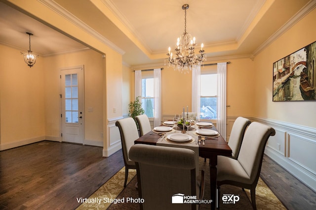 dining area featuring dark wood-type flooring, ornamental molding, a raised ceiling, and a chandelier