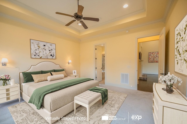 carpeted bedroom with ornamental molding and a tray ceiling