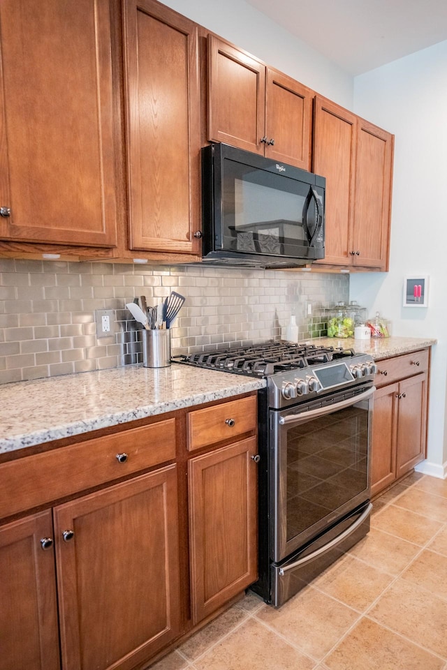 kitchen featuring light tile patterned flooring, decorative backsplash, light stone countertops, and stainless steel gas range